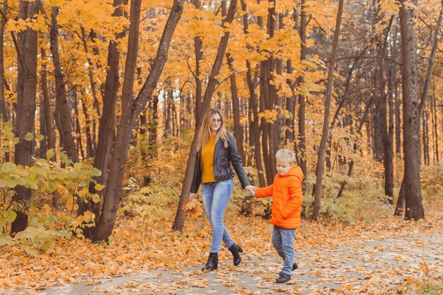 Mutter und Sohn gehen im Herbstpark spazieren und genießen die schöne Herbstnatursaison einzeln