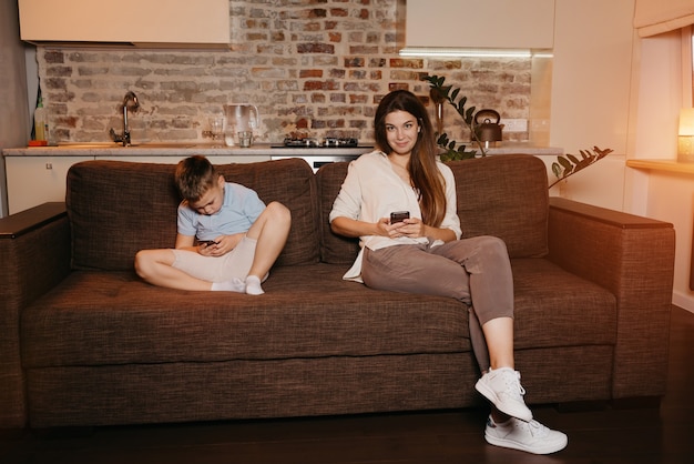 Mutter und Sohn genießen ihre Handys auf dem Sofa in der Wohnung