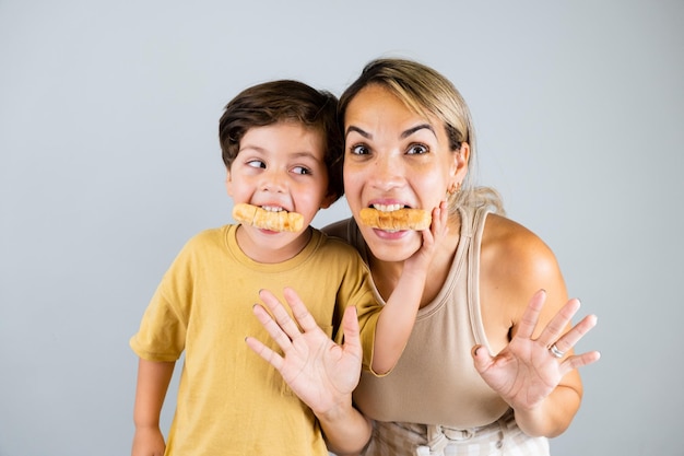 Mutter und Sohn genießen und essen einen lateinamerikanischen Snack namens Tequenos mit lustigen Gesichtsausdrücken