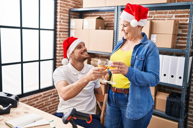 Foto mutter und sohn im e-commerce-geschäft mit weihnachtsmütze stoßen im büro mit wein an