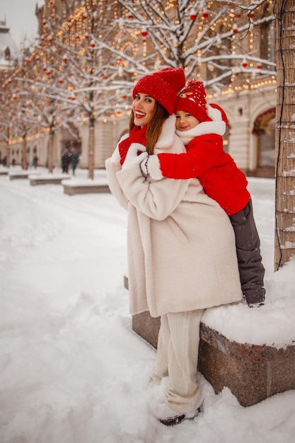 Mutter und Sohn in warmen Kleidern amüsieren sich im Winter auf einer verschneiten Neujahrsmesse