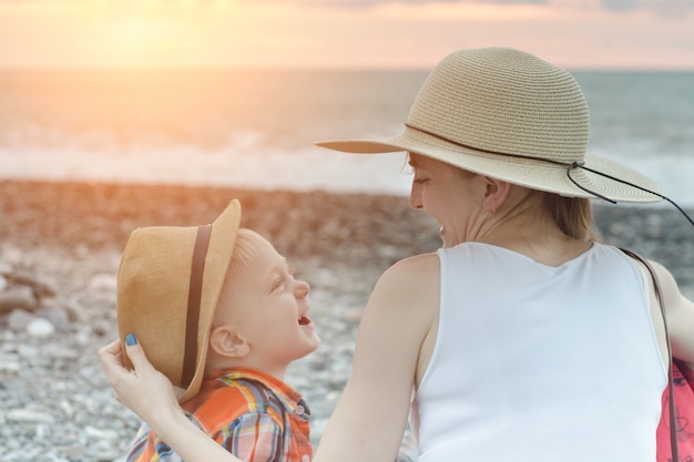 Mutter und Sohn lachen, während sie am Strand sitzen