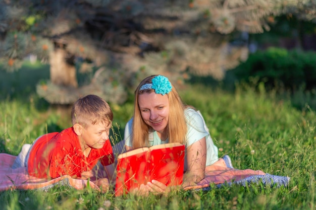 Mutter und Sohn lesen ein Buch auf einer Decke in der Natur sitzen