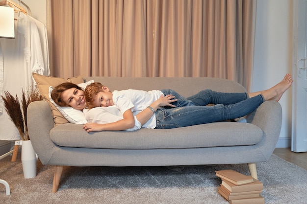 Mutter und Sohn liegen auf dem Sofa, während sie sich umarmen, fauler Tag, Mutter und Kind Momente