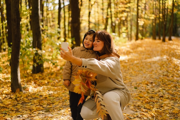 Mutter und Sohn machen ein Selfie am Telefon im Herbstwald Menschen nutzen Technik