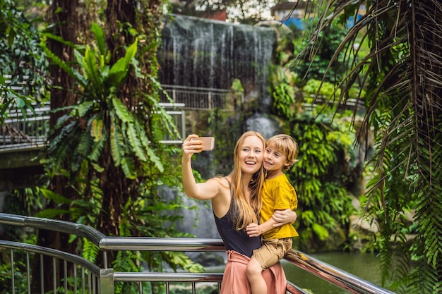 Mutter und Sohn machen ein Selfie vor dem Hintergrund eines Wasserfalls