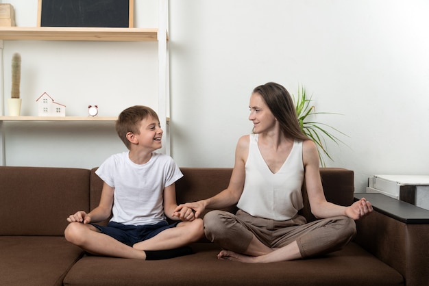 Mutter und Sohn meditieren auf der Couch