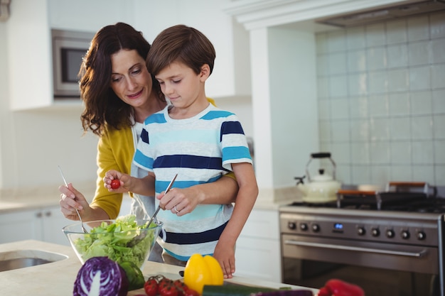 Mutter und Sohn mischen den Salat in der Küche