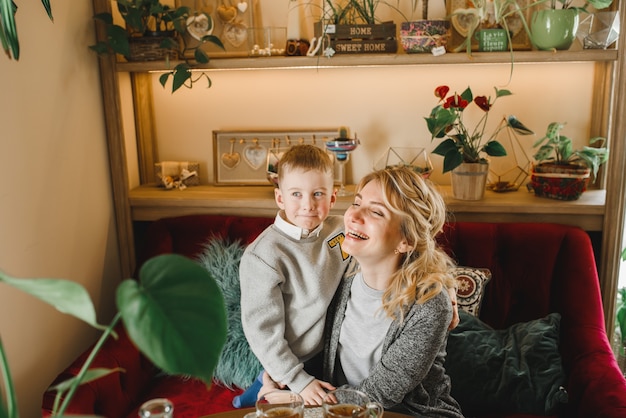 Mutter und Sohn mit Blumen im Kaffee. Sohn gibt der Mutter Blumen. süße Familie. Internationaler Frauentag, 8. März feiern