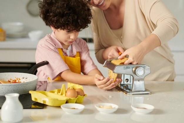 Mutter und Sohn mit Nudelmaschine