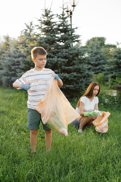 Mutter und Sohn reinigen bei Sonnenuntergang Müll im Park Recycling von Umweltabfällen
