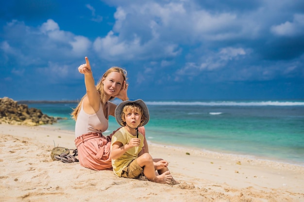 Mutter und Sohn Reisende am erstaunlichen Melasti Beach mit türkisfarbenem Wasser, Insel Bali, Indonesien. Reisen mit Kinderkonzept