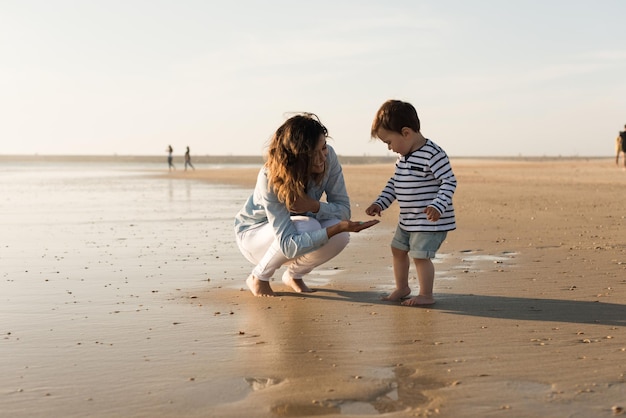 Mutter und Sohn spielen am Strand mit Sand
