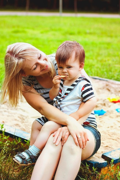 Mutter und Sohn spielen im Park und lachen an einem sonnigen Tag bei einem Sommerspaziergang. Familienurlaub