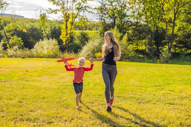 Mutter und Sohn spielen mit einem großen Spielzeugflugzeug im Park.