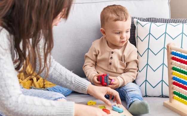 Mutter und Sohn spielen mit Mathe-Puzzle-Spiel und Auto sitzen auf dem Sofa zu Hause