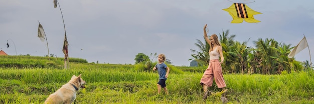 Mutter und Sohn starten einen Drachen in einem Reisfeld in Ubud, Insel Bali, Indonesien BANNER, LANGFORMAT