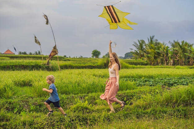 Mutter und Sohn starten einen Drachen in einem Reisfeld in Ubud, Insel Bali, Indonesien