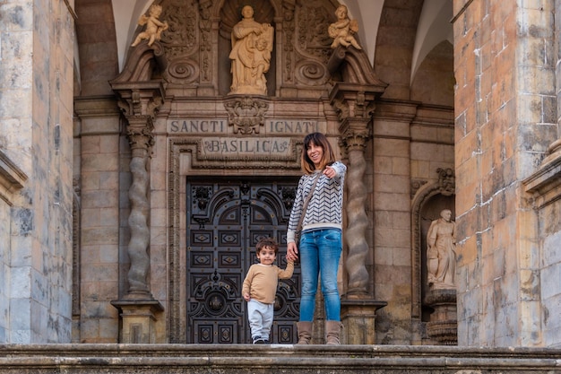 Mutter- und Sohntouristen an der Tür des Heiligtums von Loyola Barockkirche von Azpeitia