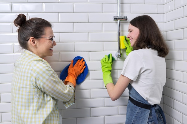 Mutter und Teenager-Tochter, die zusammen im Badezimmer säubern. Mädchen, das der Mutter hilft, zu Hause zu reinigen. Jugendliche und Eltern, Beziehungen, Sauberkeit und Haushalt, Haushaltspflichten