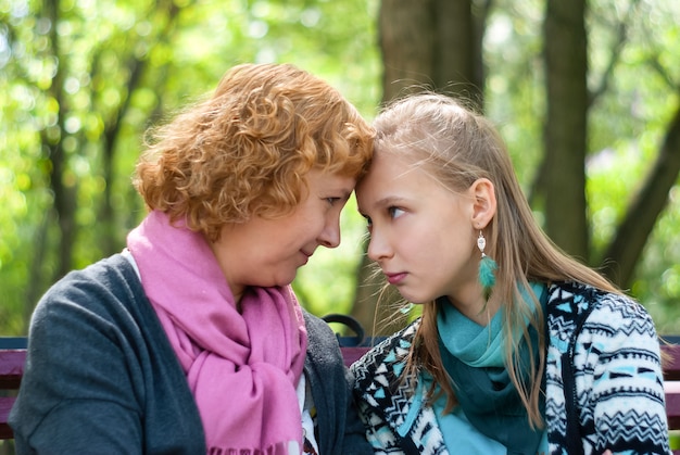 Mutter und Teenie-Tochter berühren sich die Stirn und schauen sich selbstbewusst an