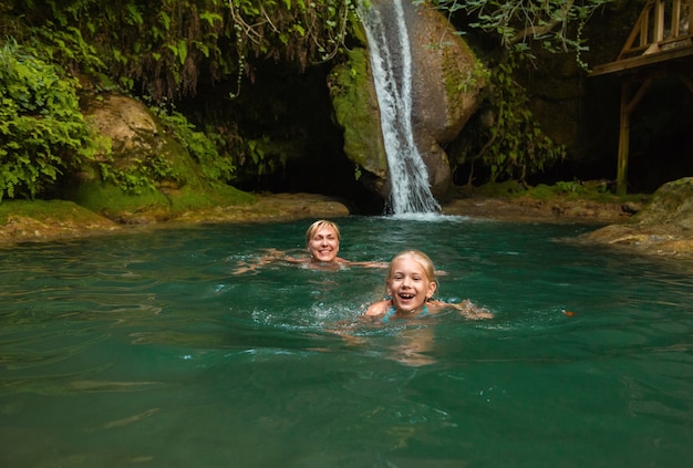 Mutter und Tochter an einem Wasserfall im Dschungel. Reisen Sie in der Natur in der Nähe eines schönen Wasserfalls, Türkei.