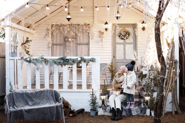 Mutter und Tochter auf der Veranda des Hauses im Winter am Weihnachtstag