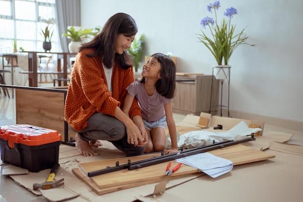 Mutter und Tochter bauen im neuen Zuhause Möbel zusammen