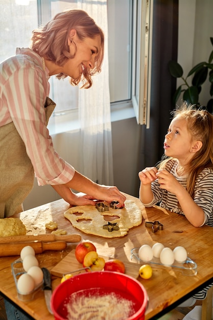 Mutter und Tochter bereiten Mehlbackwaren auf einem Tisch in der Küche zu Hause zu