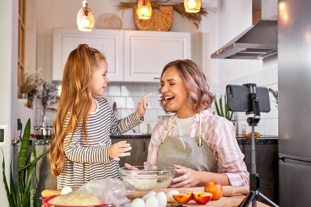 Mutter und Tochter des Food-Bloggers bereiten den Teig vor, backen Kekse, nehmen Videos vor der Kamera auf, genießen. in der Küche