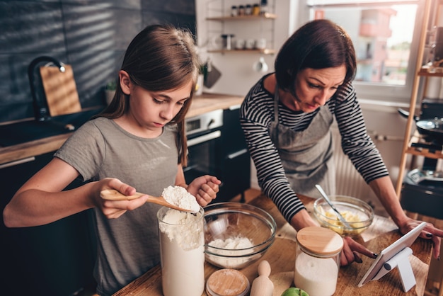 Mutter und Tochter, die Apfelkuchenrezept auf der Tablette suchen