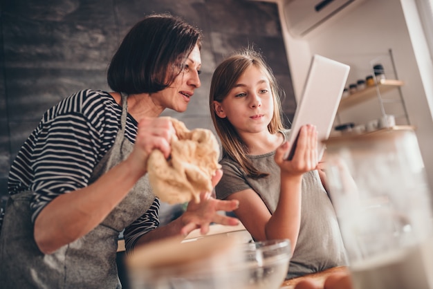 Mutter und Tochter, die Apfelkuchenrezept auf der Tablette suchen