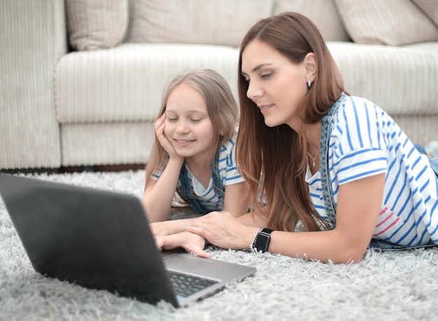 Mutter und Tochter, die einen Laptop in ihren Hausbewohnern und -technologie verwenden