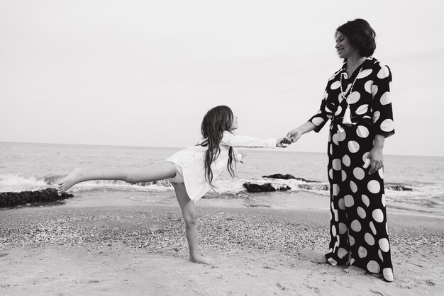 Mutter und Tochter, die Hände halten und auf Strand gehen