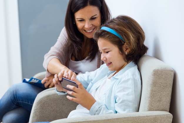 Mutter und Tochter, die Handy im Warteraum des Doktors verwenden.