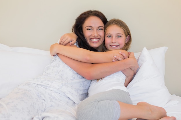 Mutter und Tochter, die im Bett umfassen