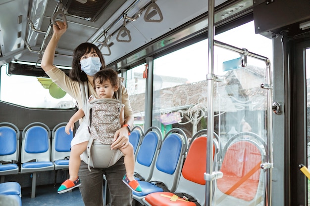 Mutter und Tochter, die öffentliche Verkehrsmittel während der Pandemie tragen Gesichtsmaske reiten