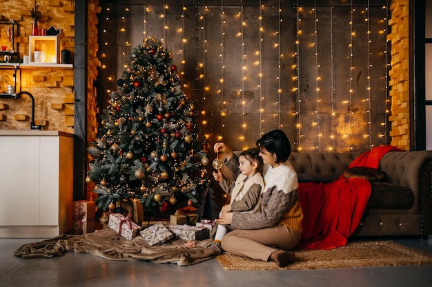 Mutter und Tochter, die Weihnachtsbaum zu Hause schmücken