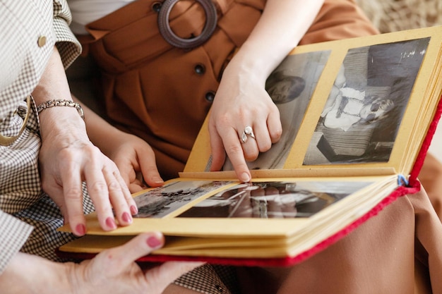 Mutter und Tochter erwägen ein Familienfotoalbum Eine ältere Frau und ein junges Mädchen halten ein Familienfotoalbum