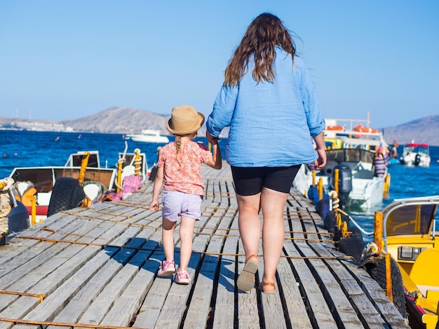 Mutter und Tochter gehen am Pier zum Boot entlang