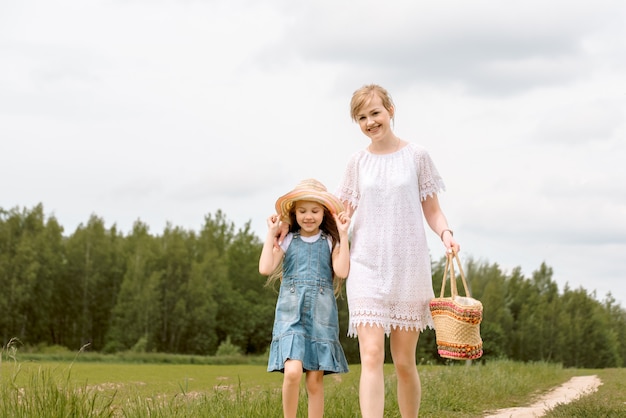 Mutter und Tochter gehen in den Wald und halten Hände.