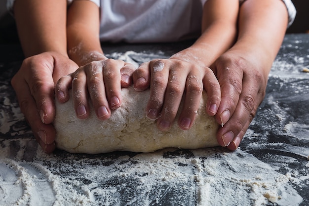 Mutter und Tochter Hände kneten Teig zusammen in der Küche.