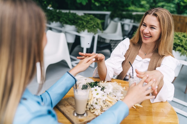 Mutter und Tochter halten Händchen im Café