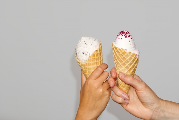 Mutter und Tochter Hands hält Eis Mais mit Milcheis. isoliert auf einer grauen Wand