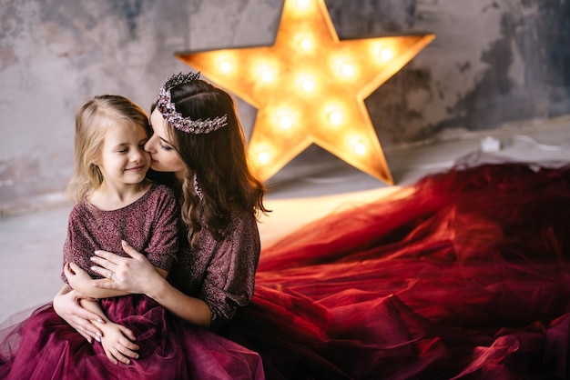 Mutter und Tochter im Bild der Königin und Prinzessin kleiden sich in den Farben von Marsala mit einem langen Zug auf dem Dachboden