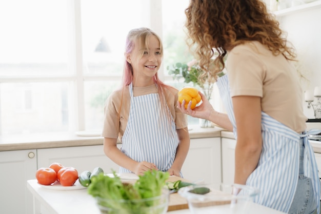Mutter und Tochter im Teenageralter, die Gemüsesalat in der Küche zubereiten