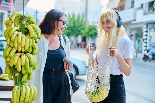 Mutter und Tochter im Teenageralter kaufen Bananen auf einem Straßenmarkt