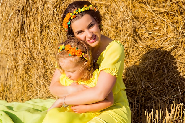 Mutter und Tochter in gelben Kleidern auf einem Heufeld