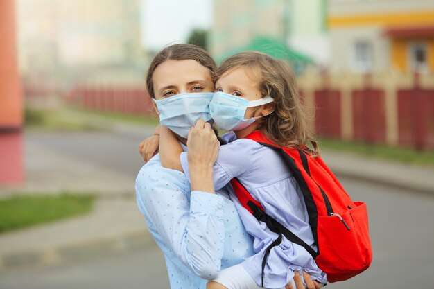 Mutter und Tochter in Gesichtsmasken gehen wieder zur Schule