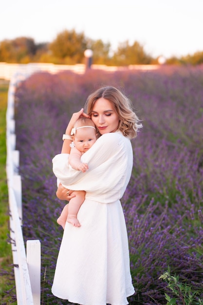 Mutter und Tochter in schönen weißen Kleidern in einem Lavendelfeld im Sommer bei Sonnenuntergang.